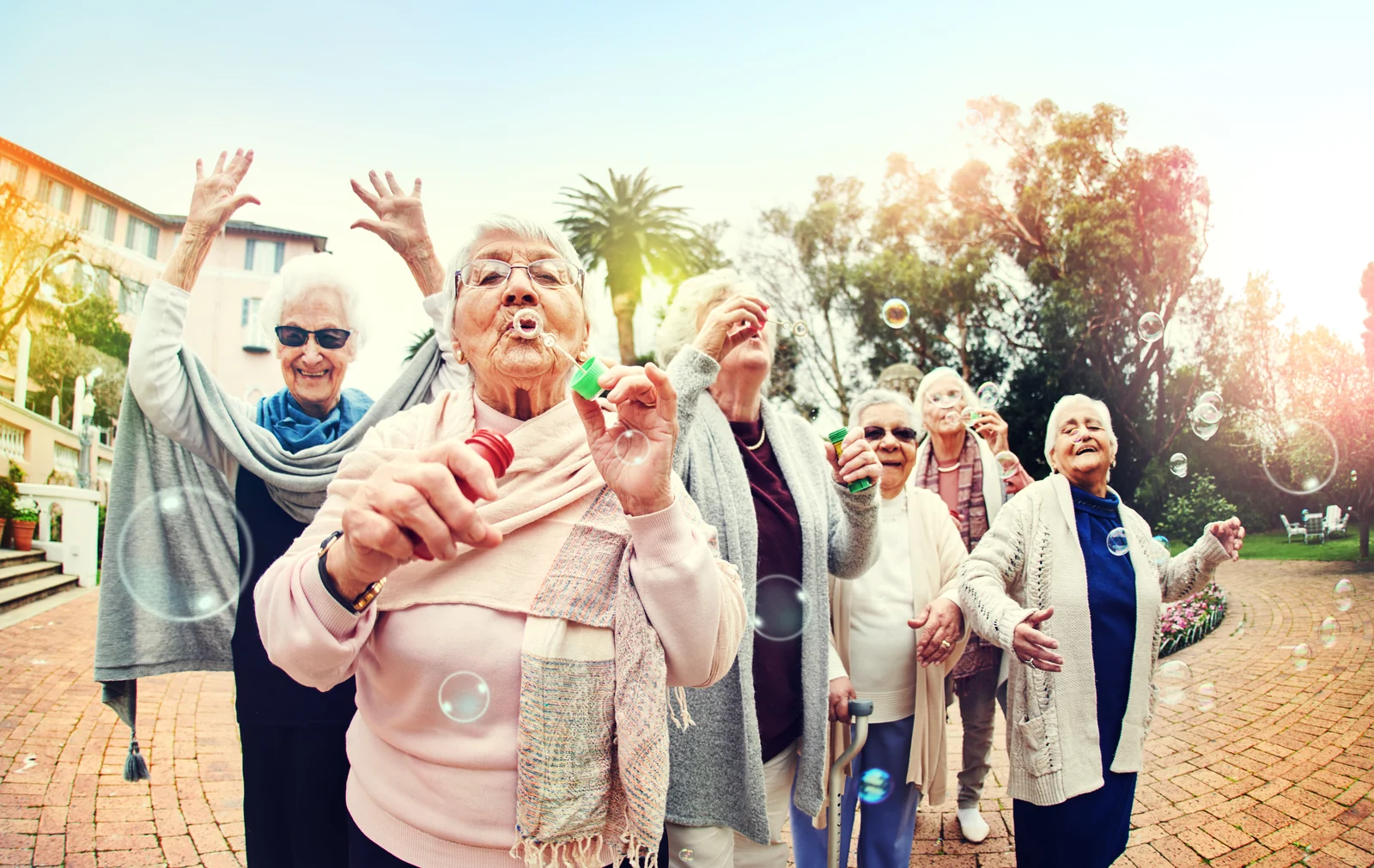 A group of older women blowing bubbles and laughing outdoors