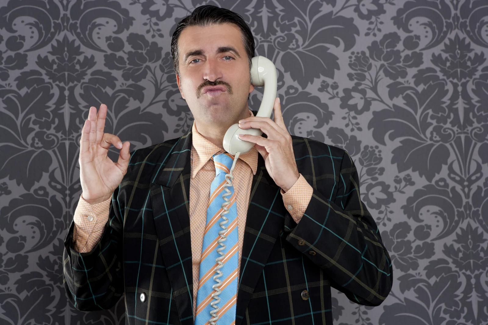 A man on the telephone, giving an OK sign