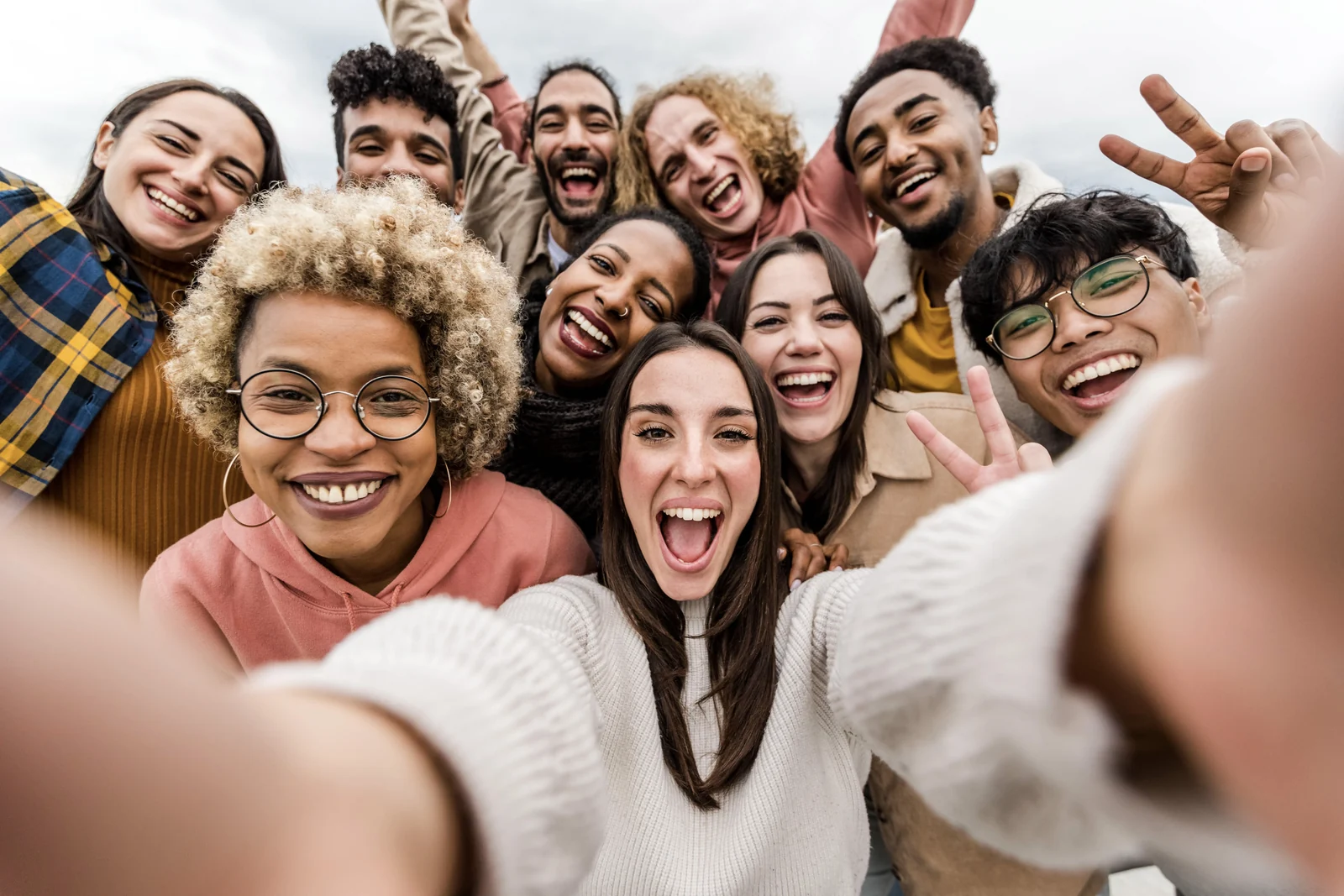 A crowd of people crowding into a selfie, laughing