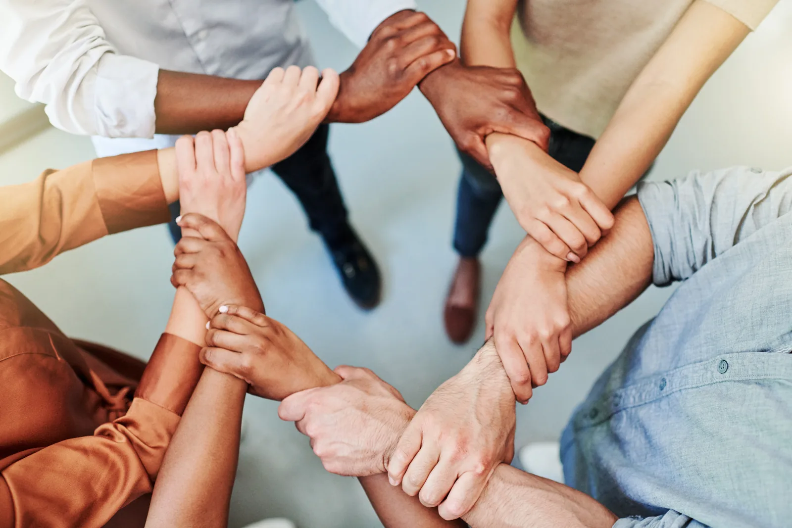 A circle of colleagues from above, each holding the next one's wrist