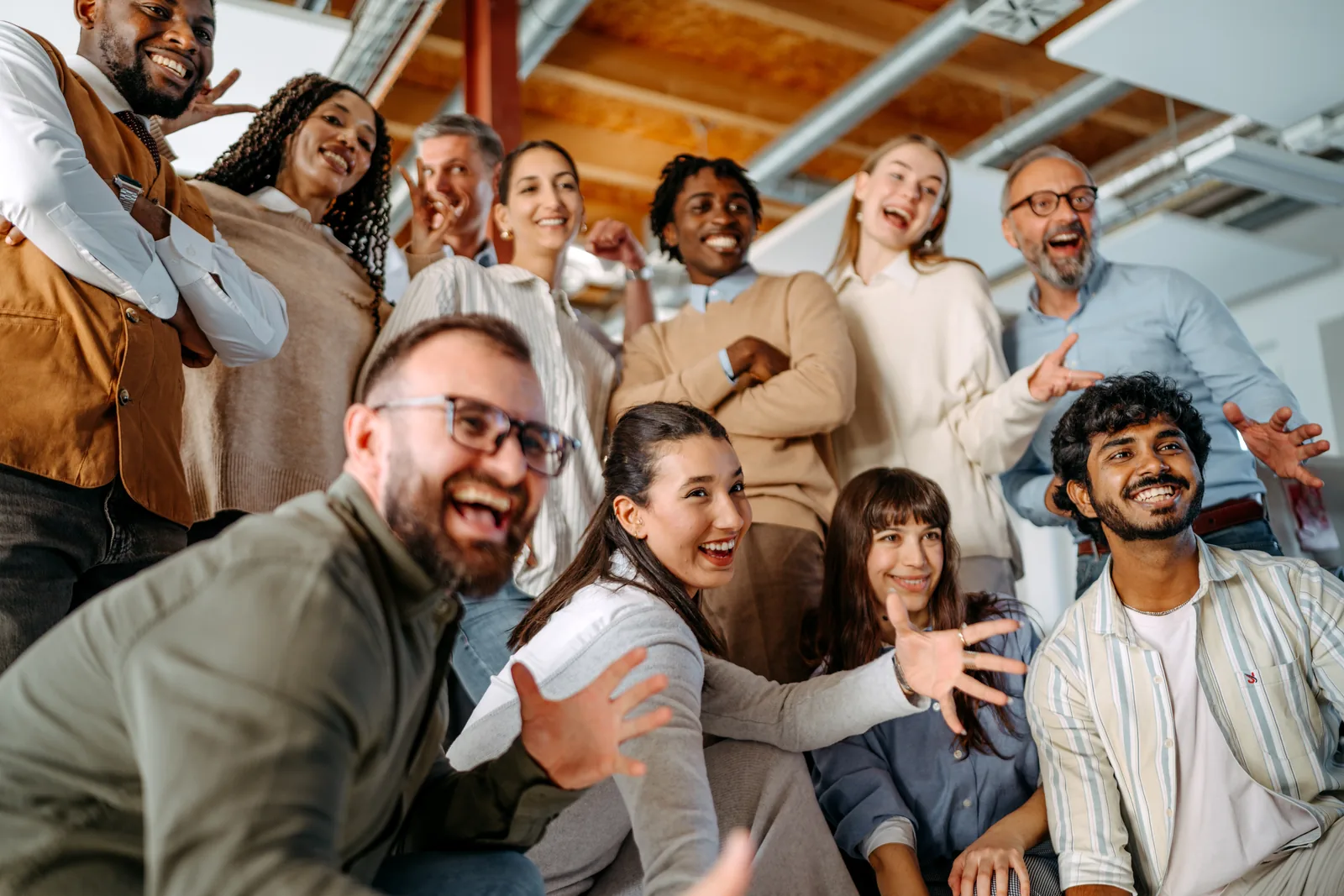 A team of colleagues gathered on an office staircase, laughing towards the camera