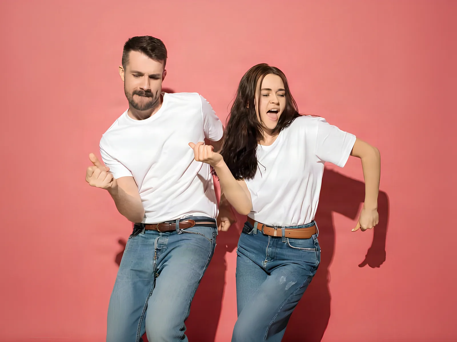 A man and a woman in white T-shirts dancing against a coral wall