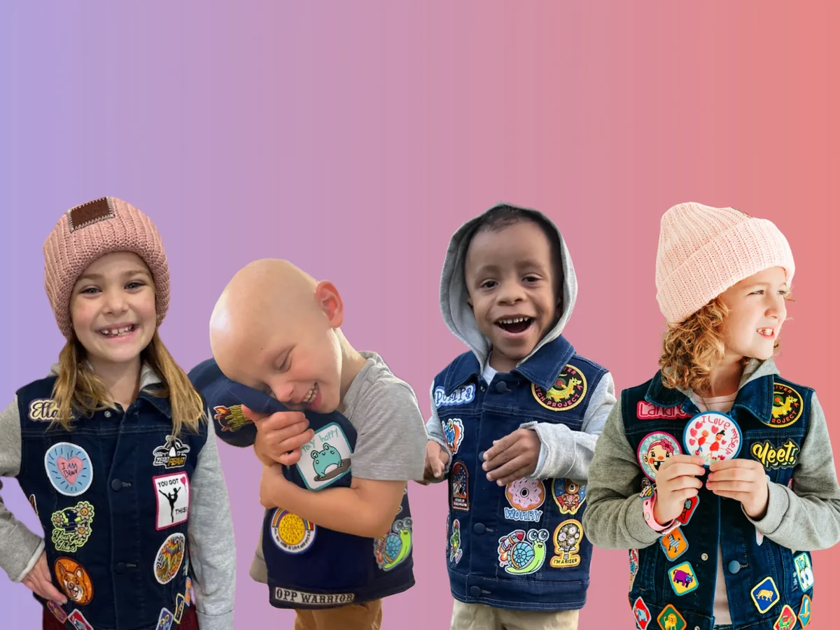 Four children in denim jackets covered in patches, smiling